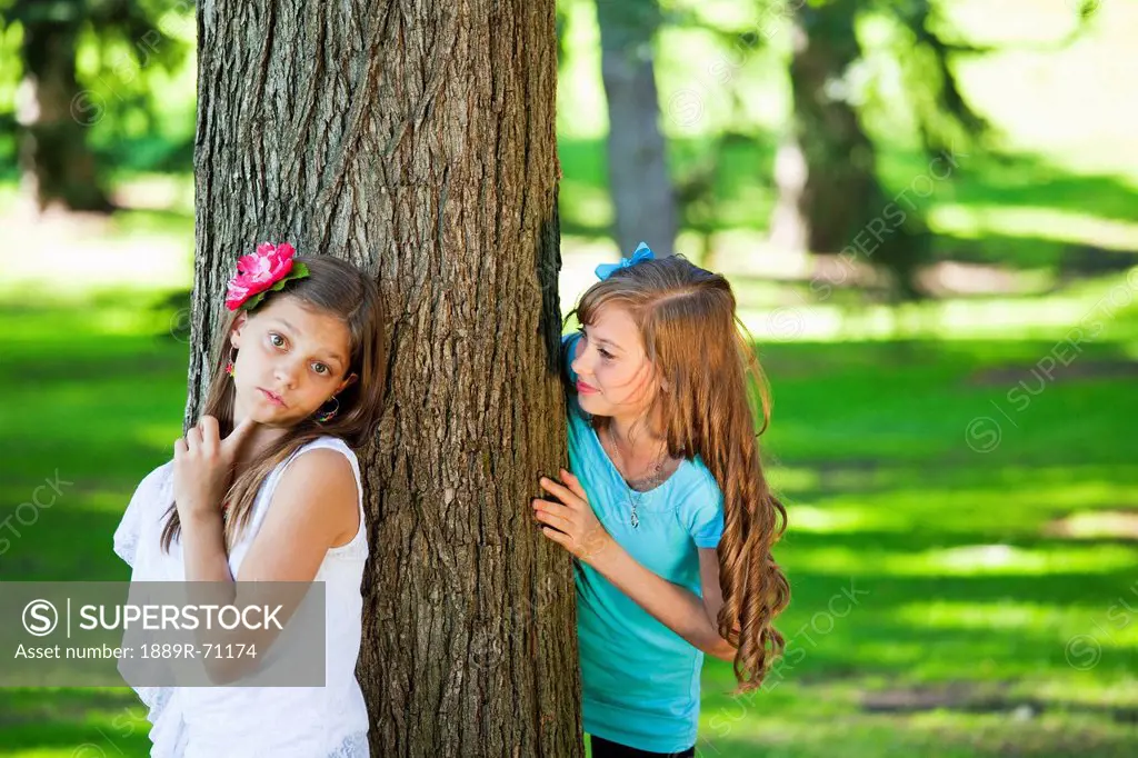 two sisters playing hide and seek in a park, edmonton alberta canada