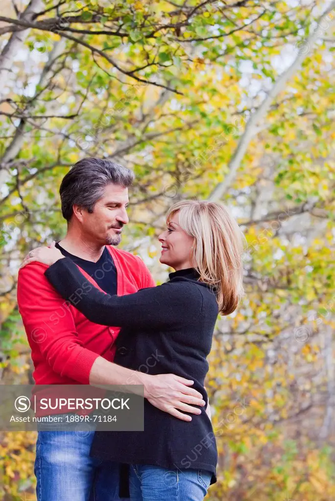 husband and wife embracing while walking in the park in autumn, st. albert alberta canada
