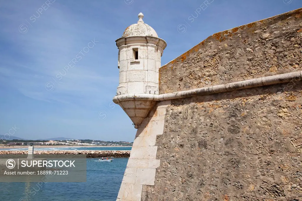 a lookout posted in the corner of a stone wall on the water´s edge, lago algarve portugal