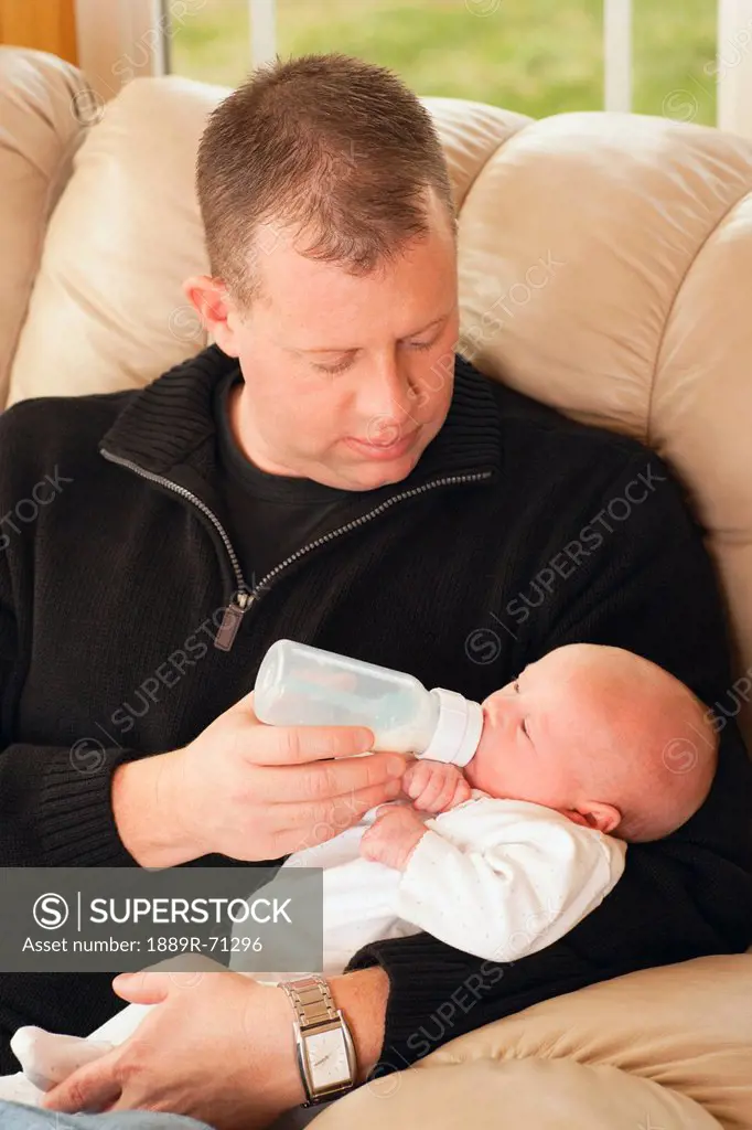 a father feeding his newborn baby from a bottle, dundas minnesota united states of america