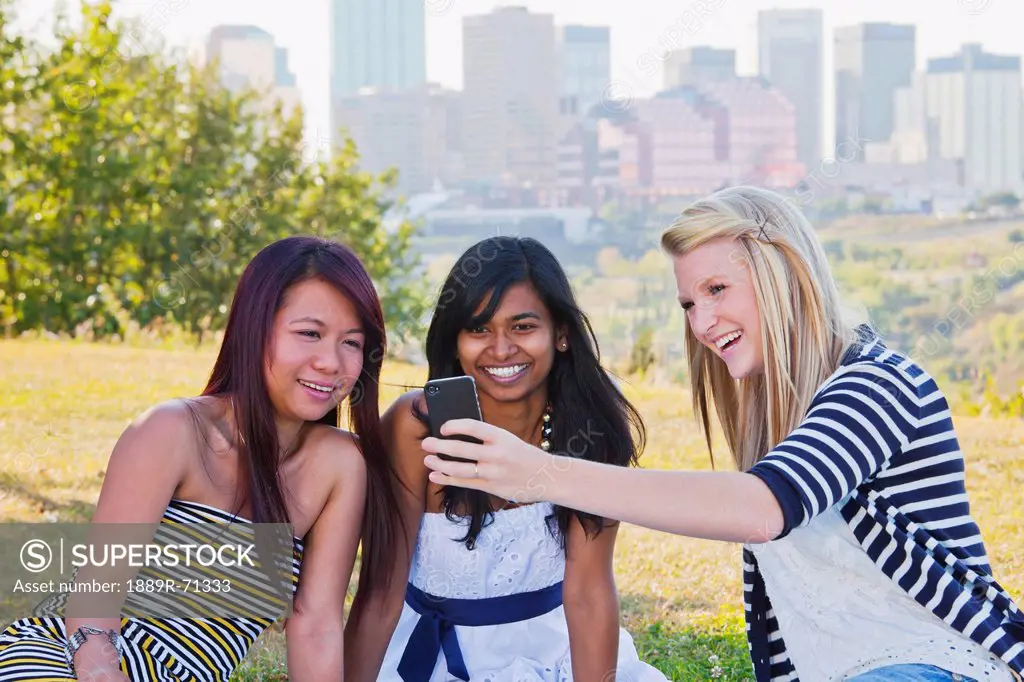friends looking at a smart phone with a city skyline in the background, edmonton alberta canada