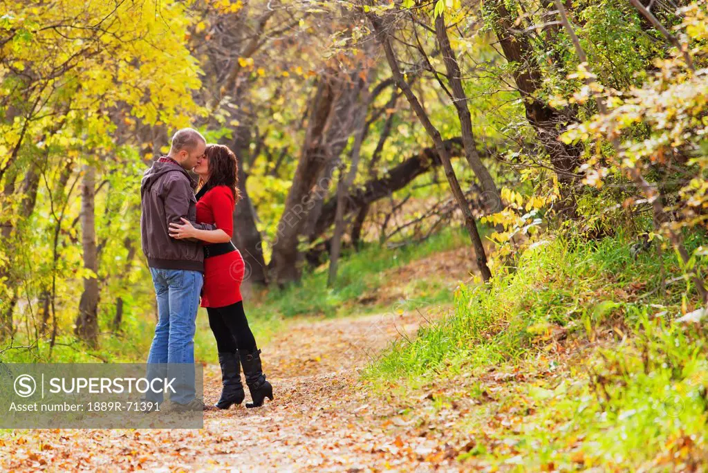 young married couple kissing while walking in a park in autumn, edmonton alberta canada