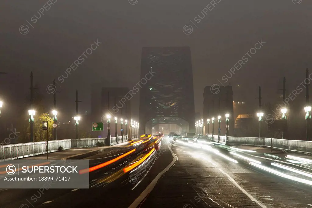 light trails of vehicle headlights and tail lights on a busy road leading to a bridge at night, newcastle northumberland england