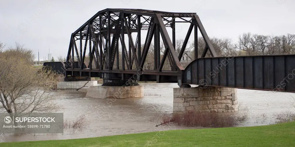 a bridge crossing assiniboine river with high waters after a flood, headingley, manitoba, canada