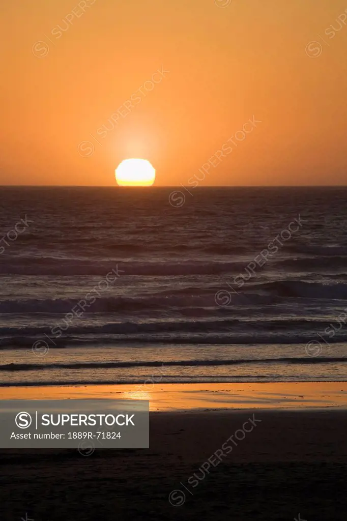 silhouette of the ocean with the sun setting on the horizon reflected in the ocean, newport oregon united states of america
