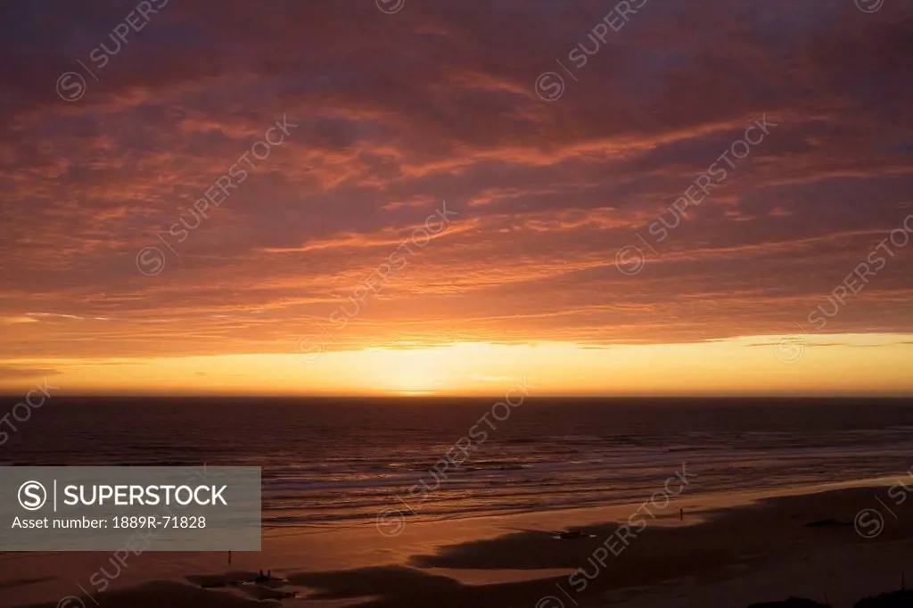 dramatic clouds at sunset on a beach with the light reflecting in the ocean, lincoln city oregon united states of america