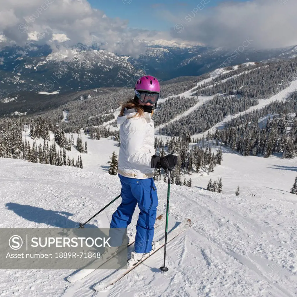 a skier on a ski trail with forests and mountains in the background, whistler british columbia canada
