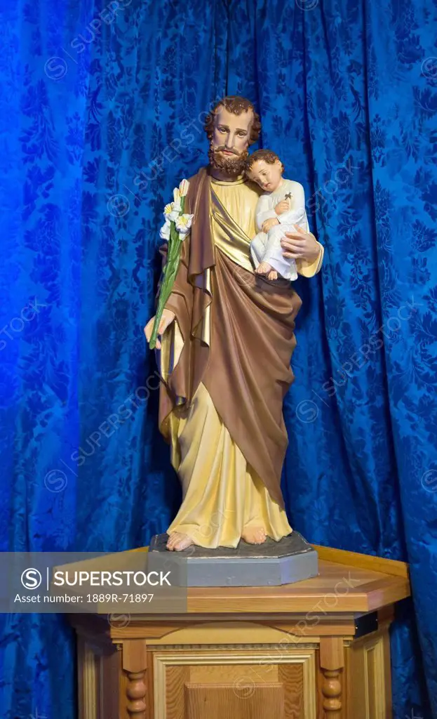 statue of jesus holding a child in front of a blue curtain, northumberland england