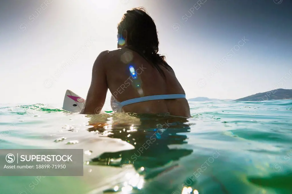 a woman sitting on a surfboard in the water, tarifa cadiz andalusia spain