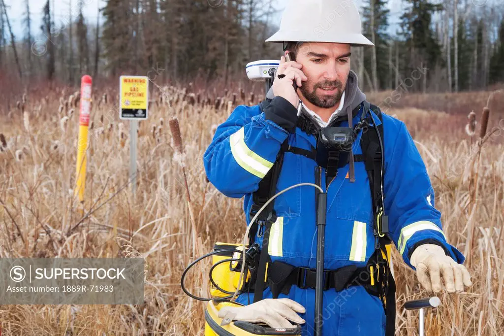 an inspector talking on the phone while inspecting pipelines, whitecourt alberta canada