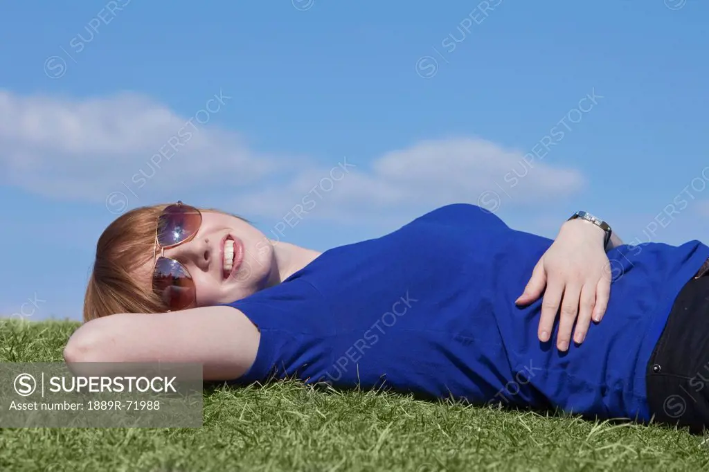 a young woman wearing sunglasses laying on the grass, edmonton alberta canada