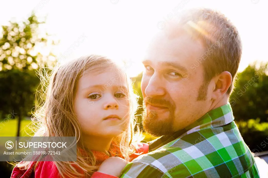 a father holds his daughter in the sunlight, bellingham washington united states of america