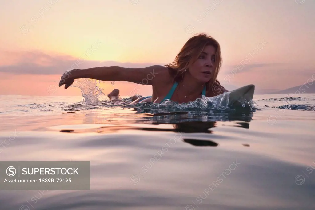 a woman paddling on a surfboard at sunset, tarifa cadiz andalusia spain