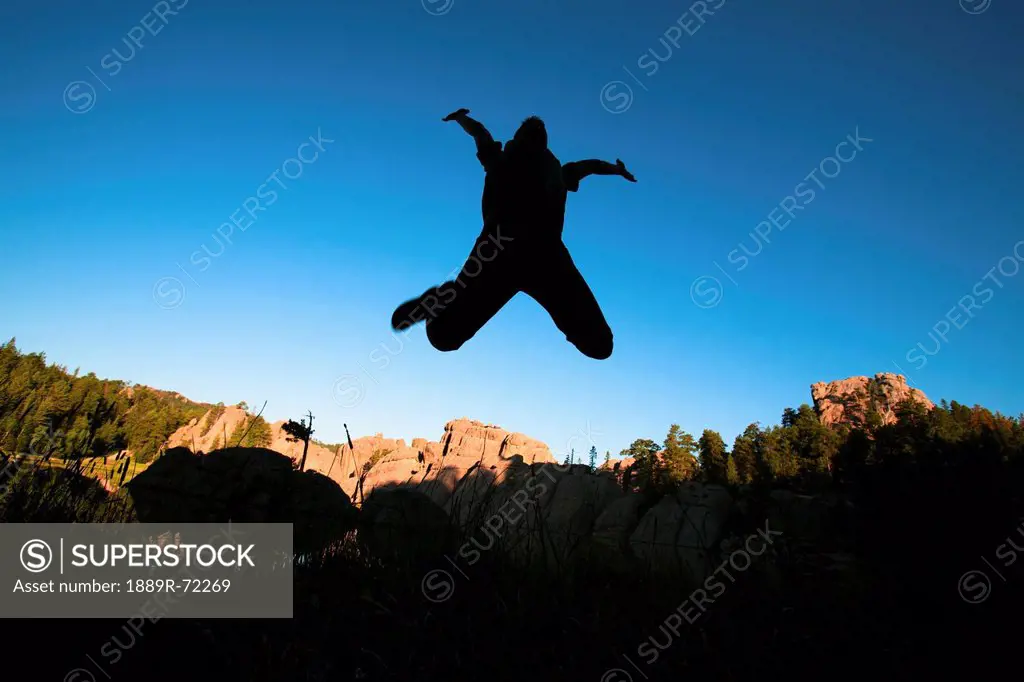 silhouette of a person jumping in the air against a blue sky, black hills south dakota united states of america