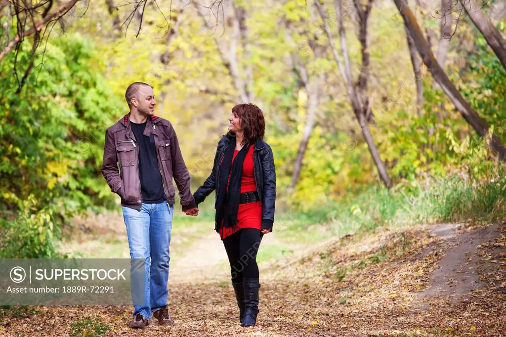 young married couple walking and talking together in a park in autumn, edmonton alberta canada