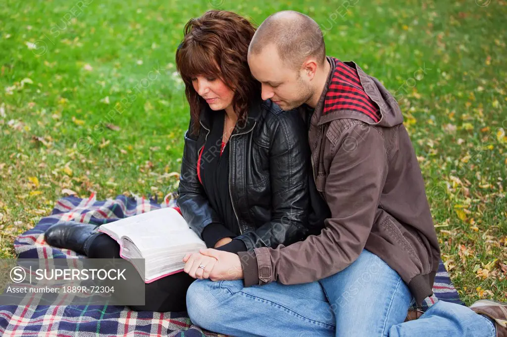 couple reading bible and praying together in the park, edmonton alberta canada