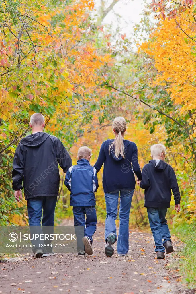 family walking together on a path in a park in autumn, edmonton alberta canada