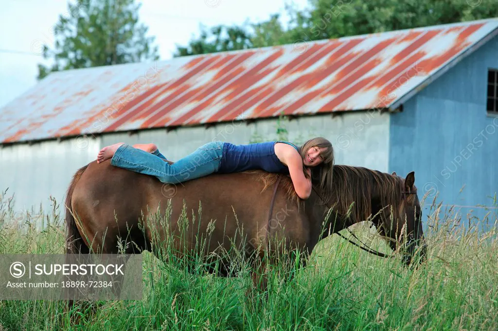 girl laying down on the back of a horse, troutdale oregon united states of america