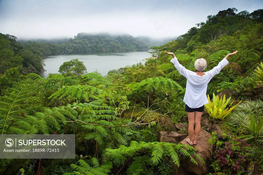 a female tourist stands among tropical plants that grow around the twin lakes at twin lakes national park, island of negros philippines