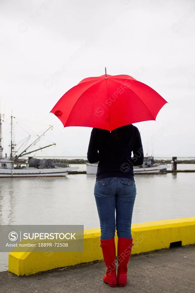 woman on a pier with a red umbrella and rain boots, richmond british columbia canada