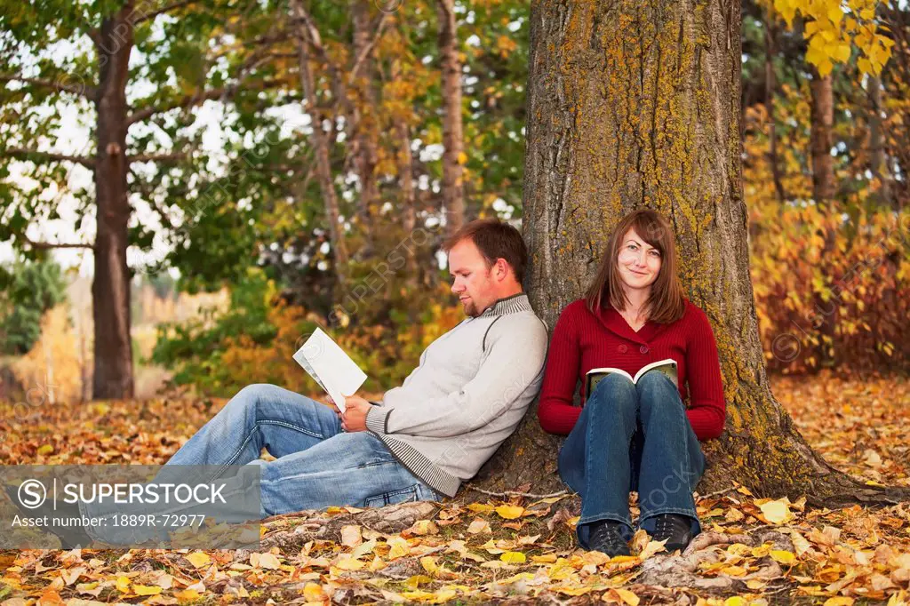 Young Married Couple Reading In A Park In Autumn, Edmonton Alberta Canada