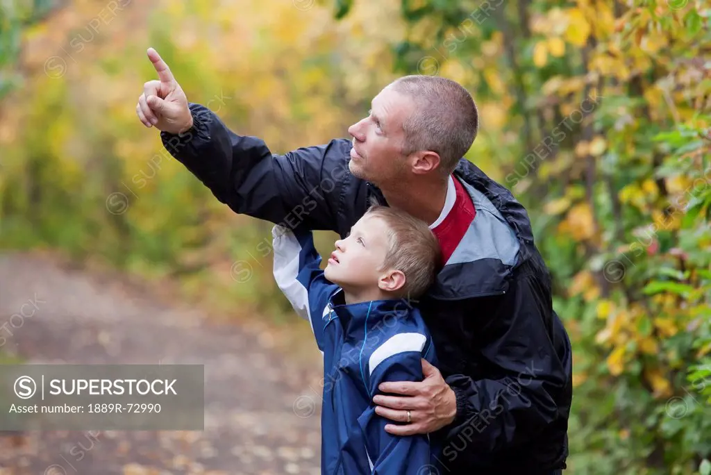 Father And Son Looking At Wildlife On A Path In The Park, Edmonton Alberta Canada