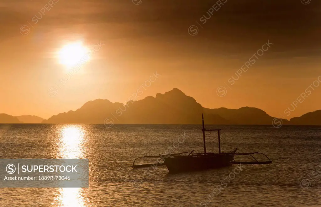 A Boat Is Silhouetted In The Water At Sunset, Corong Corong Bacuit Archipelago Palawan Philippines