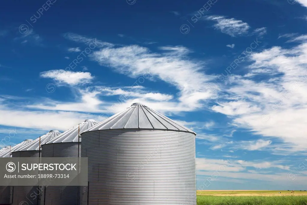 Metal Grain Bins With Blue Sky And Clouds South Of Cochrane, Alberta Canada
