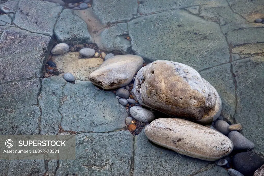 Rocks sitting in the crack of a rock slab covered with clear water, south shields tyne and wear england