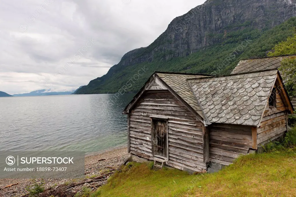 A weathered wooden house along the water´s edge, hardangervidda norway