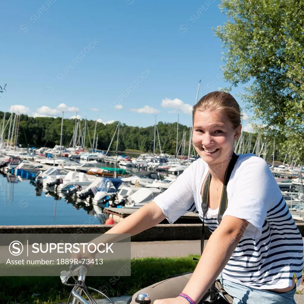 A girl on a bike with boats in the harbour in the background, oslo norway