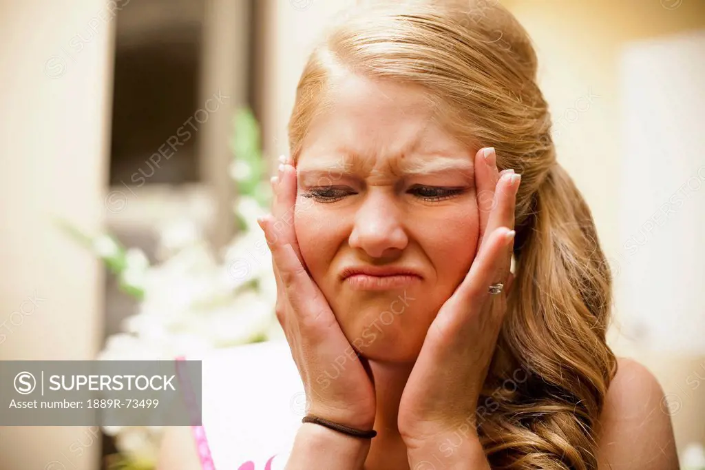 A woman holding her face in her hands with an unpleasant expression, grand junction colorado united states of america