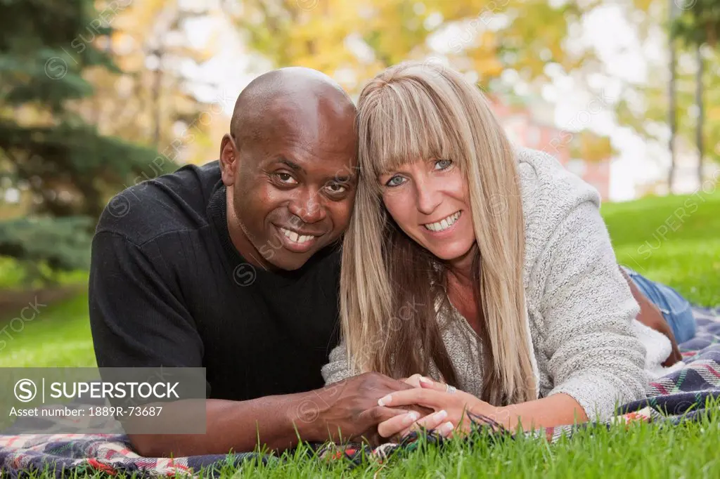 Interracial Couple Cuddling On A Blanket In A Park, Edmonton Alberta Canada
