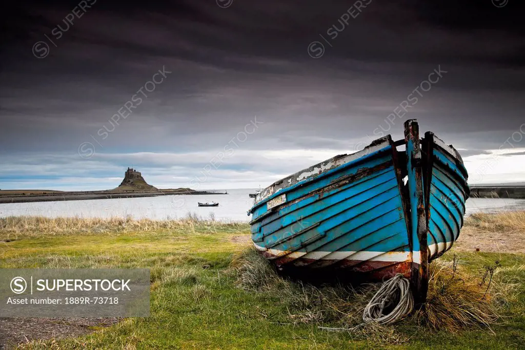 A Weathered Boat Sitting On The Shore With Lindisfarne Castle In The Distance, Lindisfarne Northumberland England