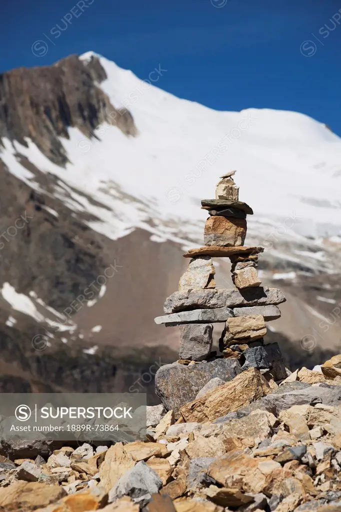 Trail Marker Cairn On Rocky Ridge With Glacier Capped Mountain And Blue Sky, Field British Columbia Canada