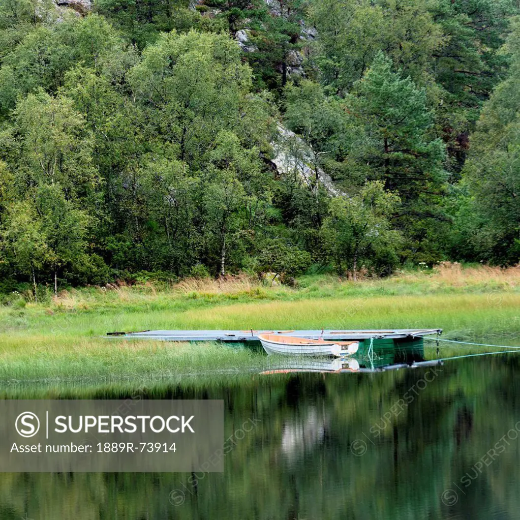 A boat moored beside a dock in tranquil water, hardangervidda norway
