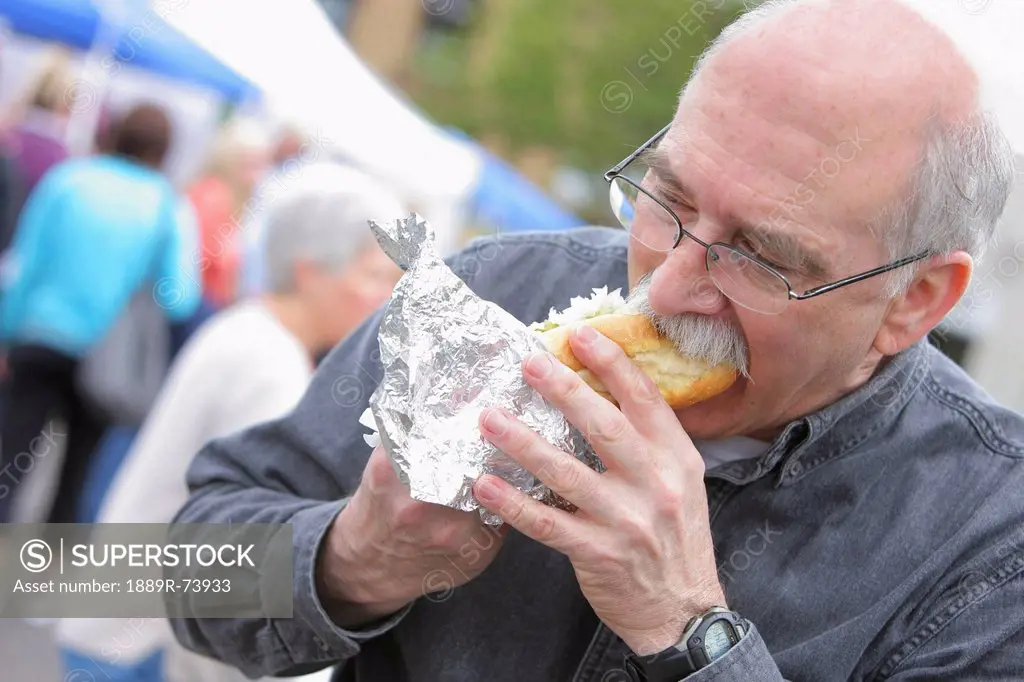Senior man biting into a hot dog, troutdale oregon united states of america
