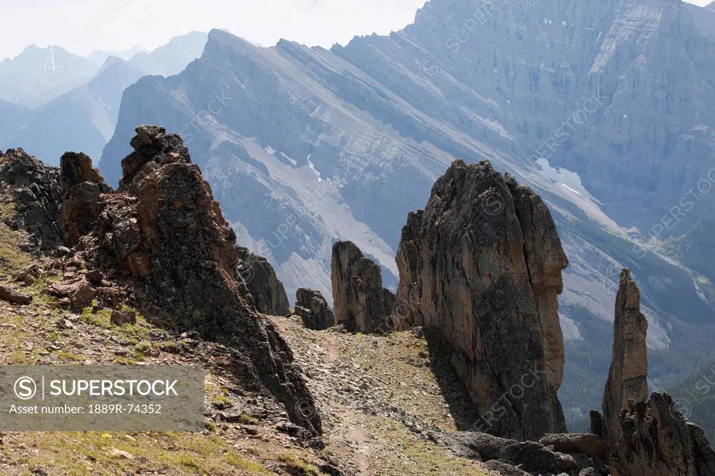 Large Rock Sentinels On Mountain Ridge With A Mountain Range In The Distance, Alberta Canada