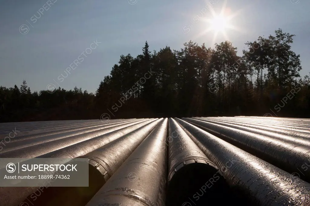 Close Up Of Drilling Pipes With Sunburst Trees And Blue Sky In The Background Near Drayton Valley, Alberta Canada