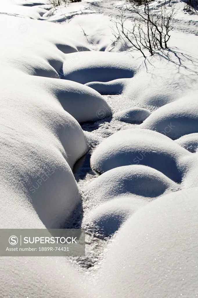 Snow covered creek with rounded contoured banks, alberta canada