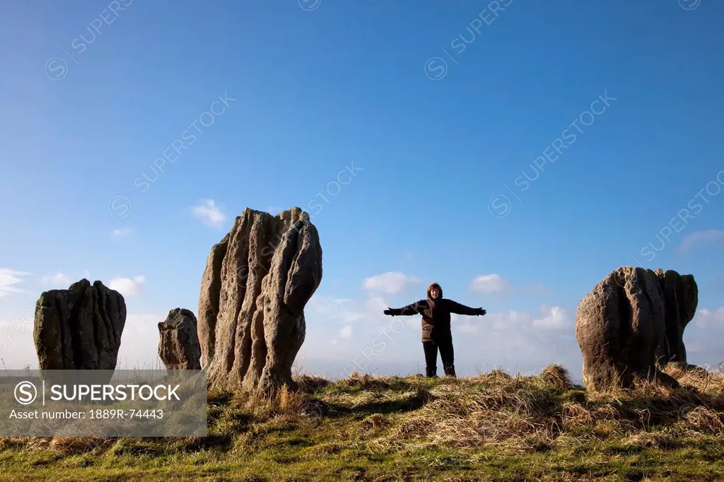 A woman standing beside the standing stones of duddo, northumberland england