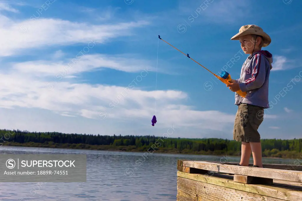 A boy fishing off a dock, lake wabamun alberta canada