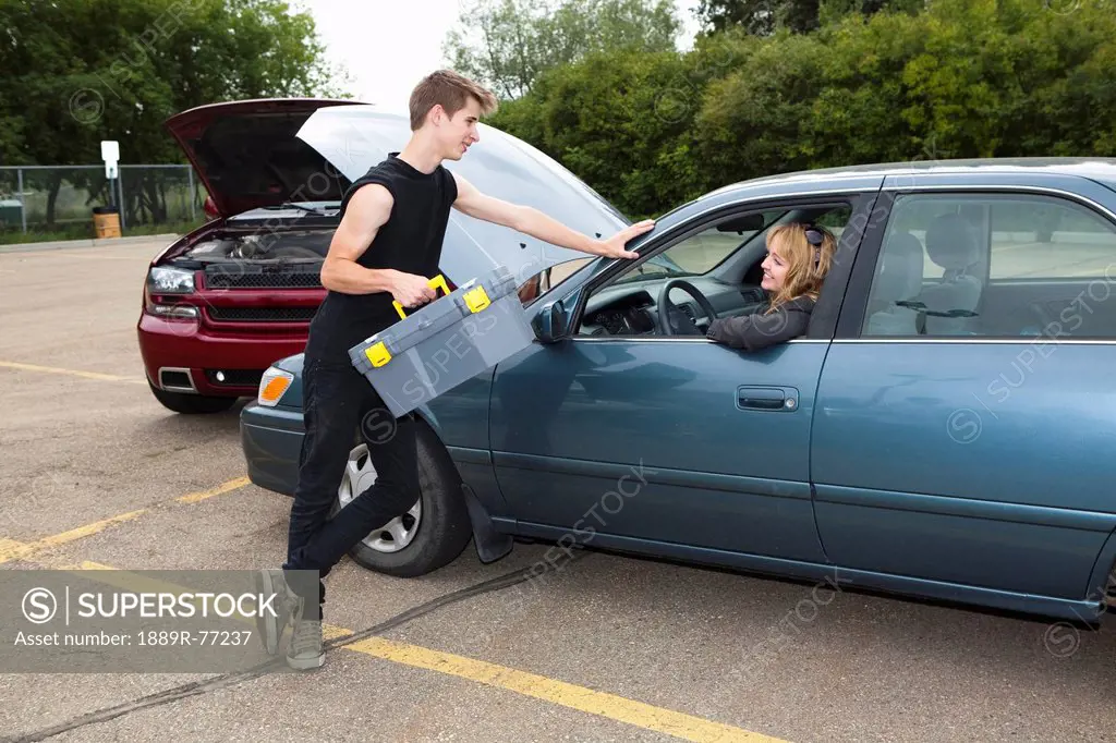 a young man helps a woman with car trouble, edmonton, alberta, canada