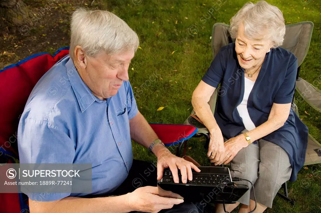 a senior man and woman sitting together using a laptop computer, edmonton, alberta, canada