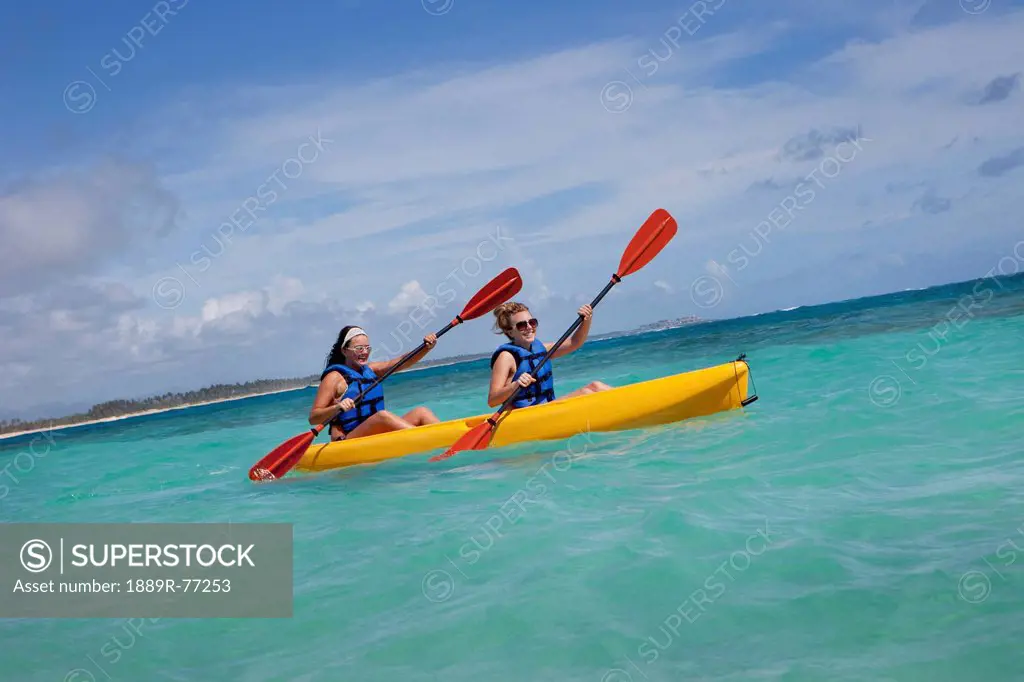 Two women in lifejackets paddling in a yellow boat, punta cana la altagracia dominican republic