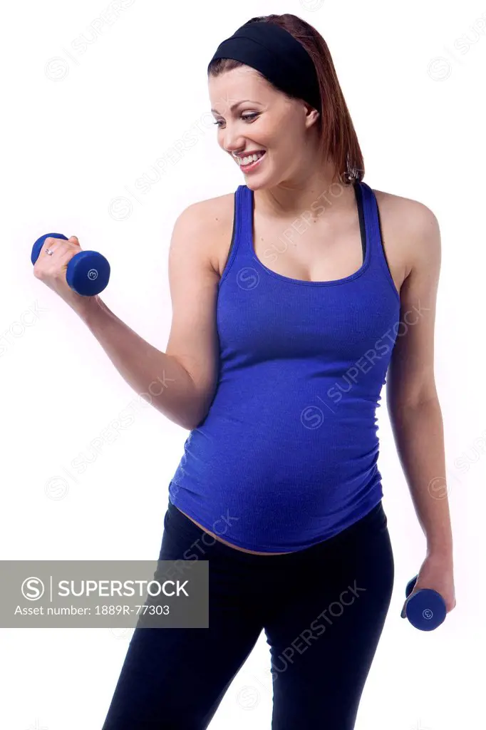 A pregnant woman uses dumbbells for fitness, edmonton alberta canada