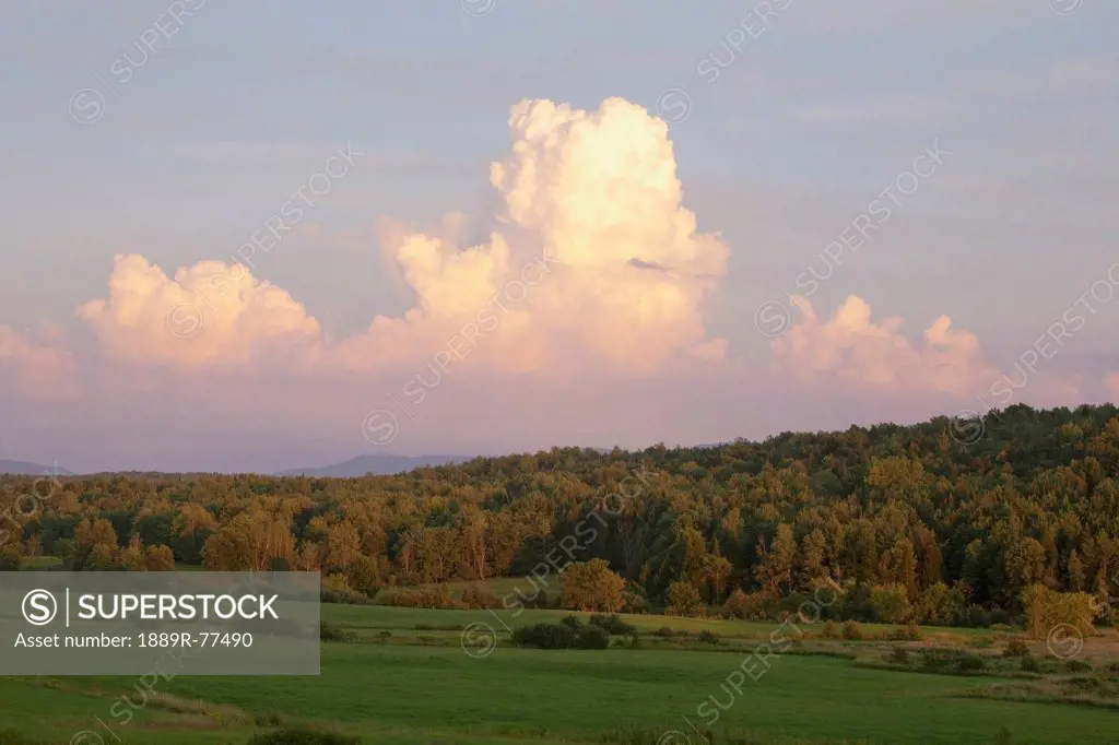 clouds in the sky above a forest at sunset, iron hill, quebec, canada