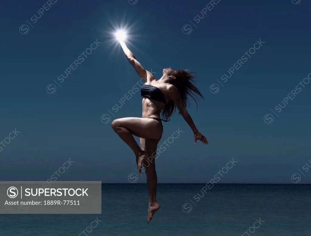 A Woman Leaping Above The Water Holding A Light In Her Hand, Tarifa Cadiz Andalusia Spain