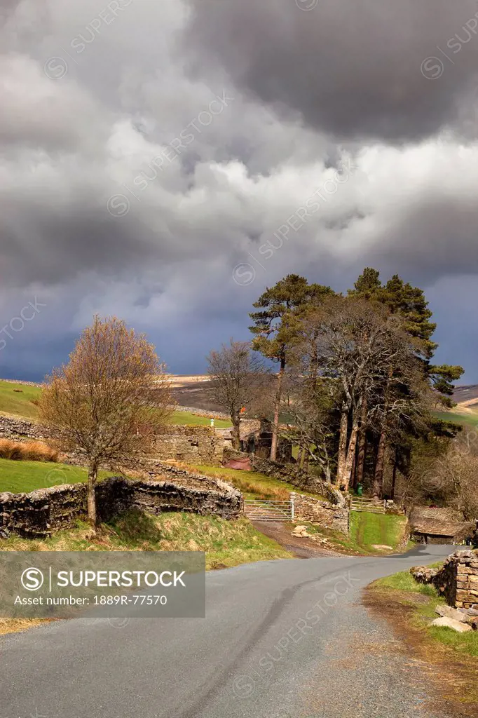 A stone fence along a road under storm clouds, swaledale england
