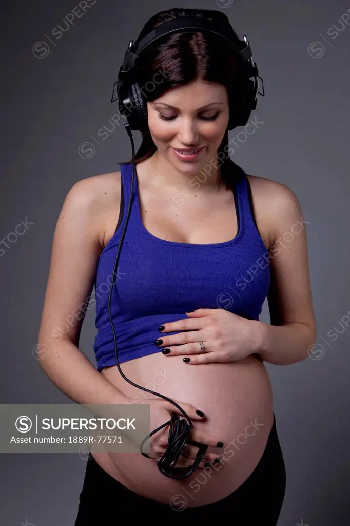 A pregnant woman with a headset plugged into her belly to hear the sounds of her unborn baby, edmonton alberta canada